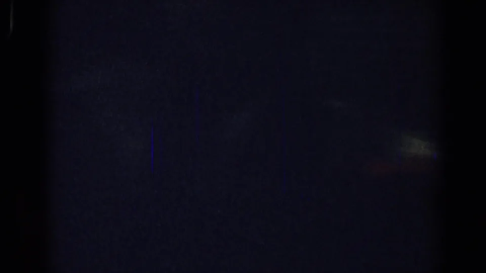 Dark 1967 home-movie frame with a barely visible interior shape, heavy grain, and low exposure.
