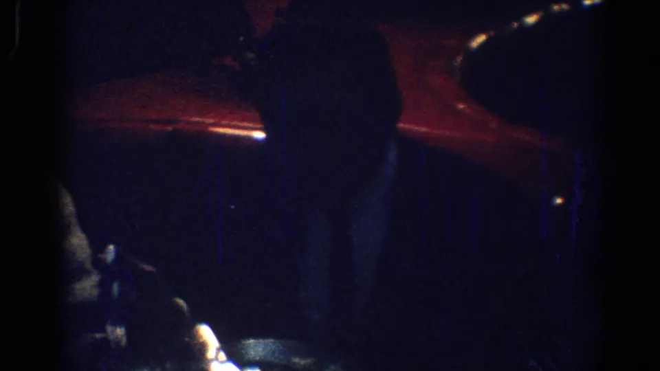 Final 1967 Los Angeles restaurant frame with red booth tones, shadowed seated figures, and the woman partly visible at the table.