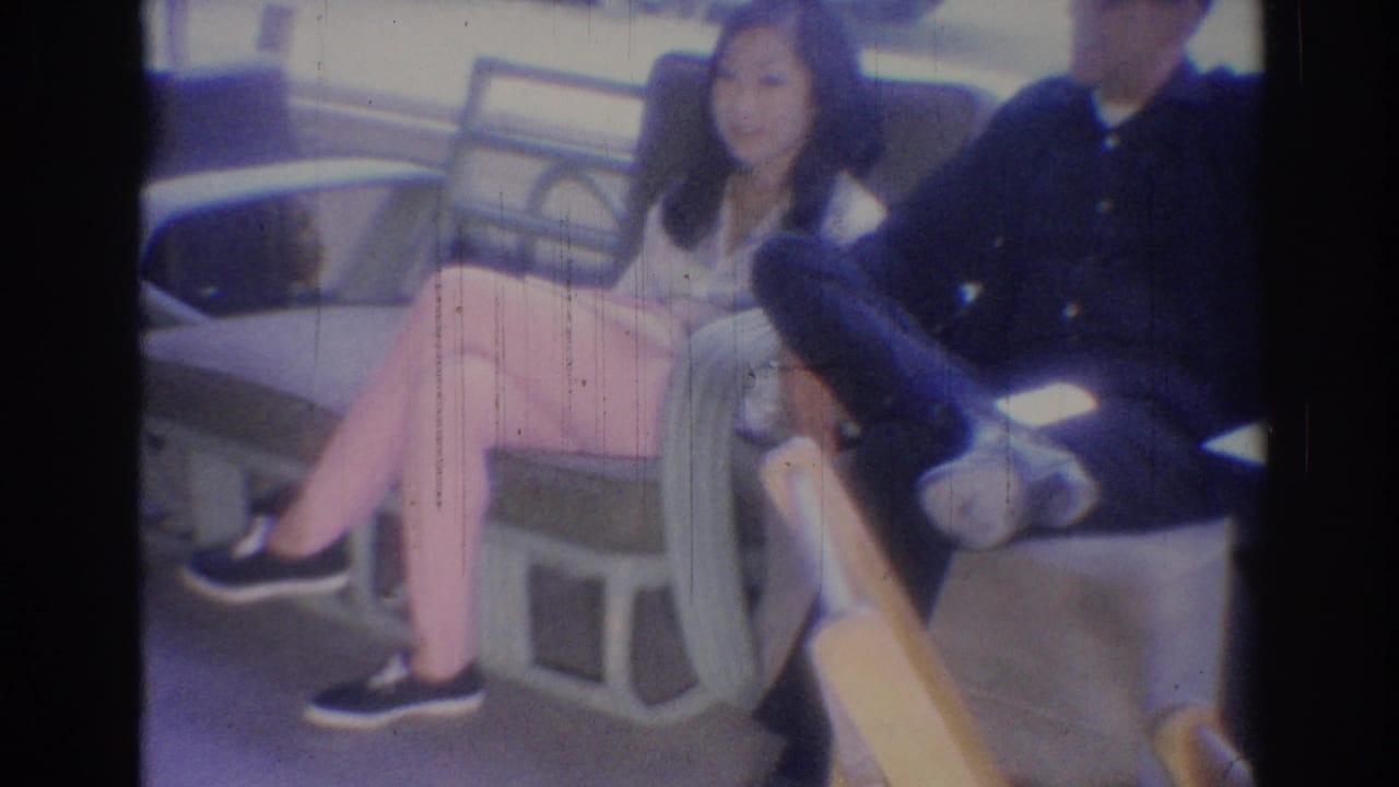 Two adults seated side by side on a public bench, with a woman facing the camera.