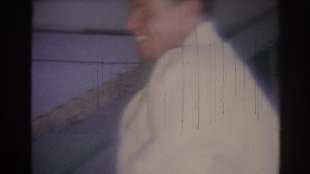 Soft, blurred view of a man in a white judo uniform inside a gym.