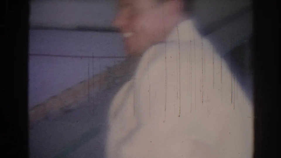 1967 Los Angeles 8mm frame showing a blurred man in a white judo gi in an indoor gym setting.