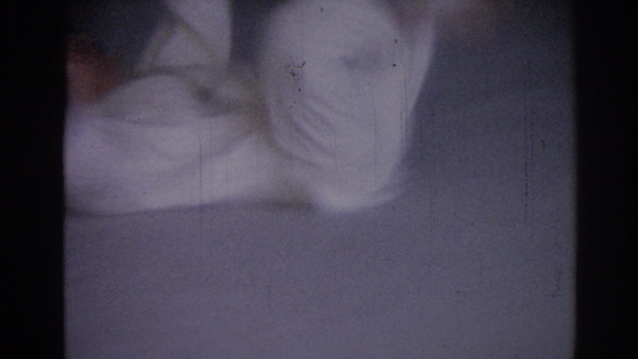 Partial view of a person in a white gi moving on a mat.