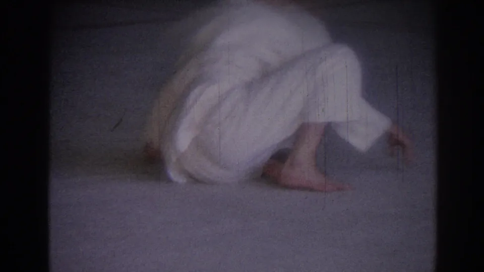 1967 home-movie frame showing the judo athlete crouched low on the mat during a practice movement.