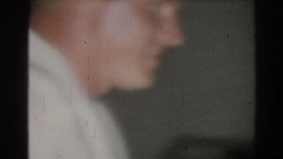 1967 Los Angeles 8mm frame showing a softly focused side profile of a young man in a white judogi in a dim interior.