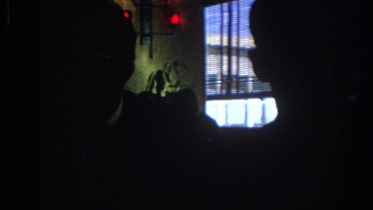 Dark interior with silhouetted people near a bright window with blinds.