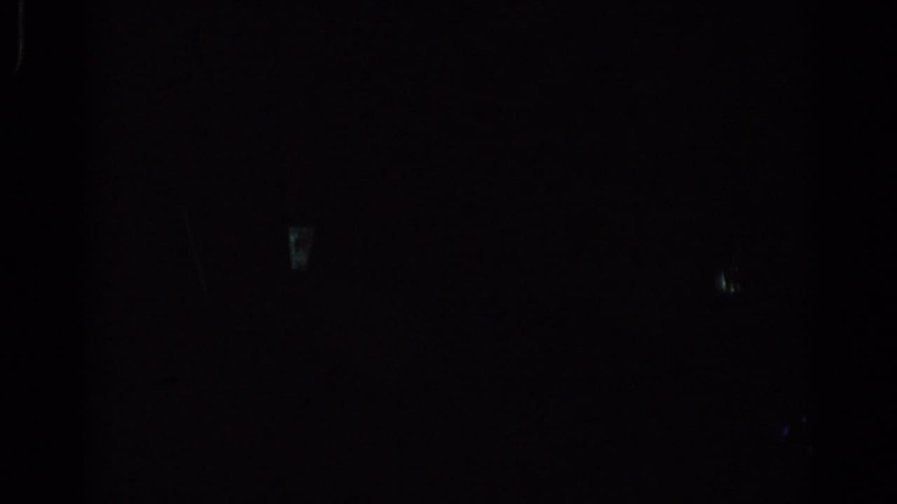 Underexposed room with figures in silhouette and bright window light.