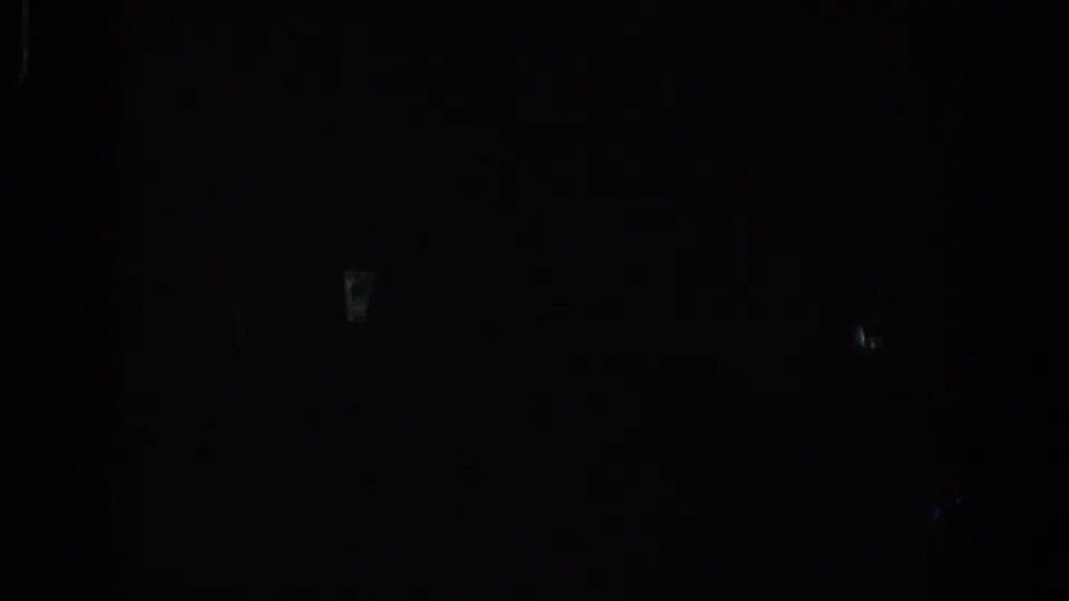 Dim 1967 Los Angeles interior frame with dark human outlines against a bright window and small red lights in the background.