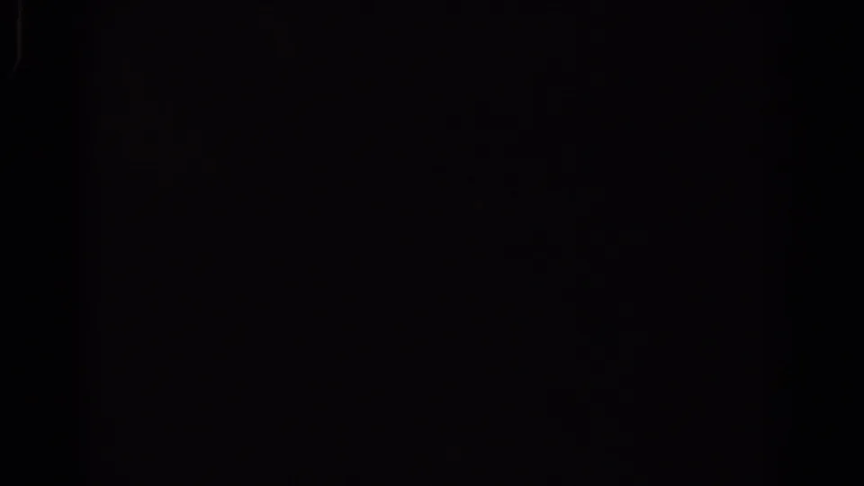 Dark 8mm frame from the start of the 1967 Los Angeles train clip, with faint blue light leaks and film-edge artifacts.