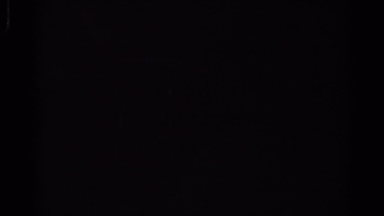 Very dark frame with faint grain and a slight blue vertical light mark.