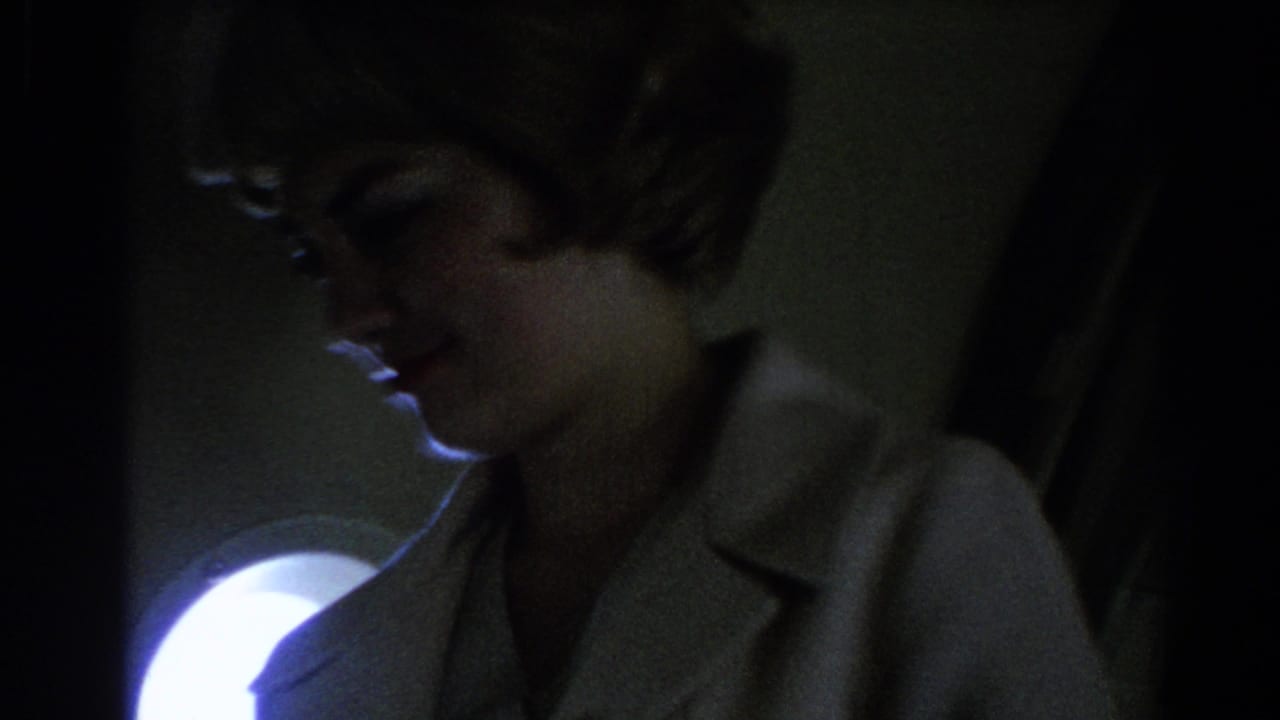 Stewardess in a light uniform seen close up in a dim airplane cabin.