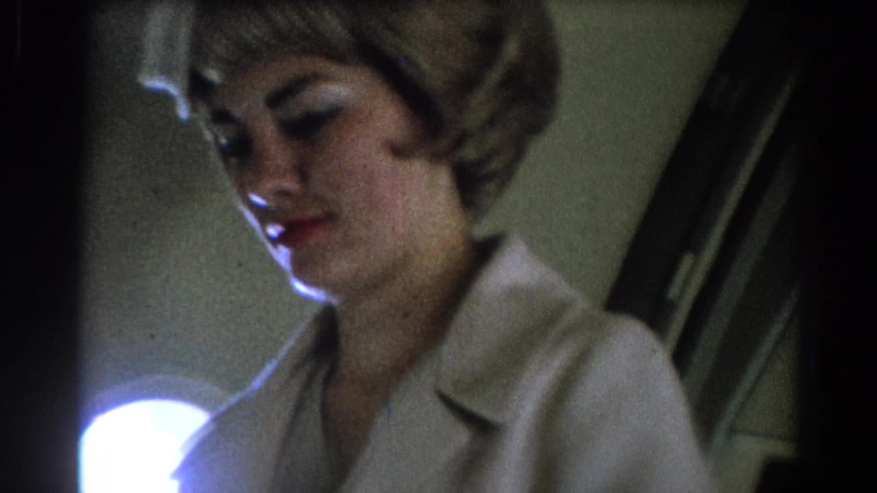 Stewardess looks downward beside a bright round cabin light or window.