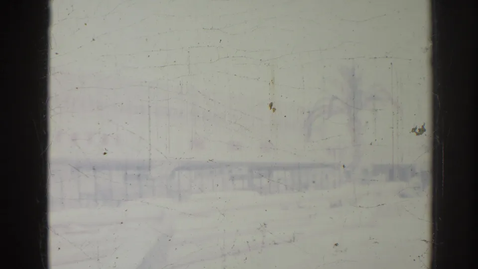 1967 Los Angeles home-movie frame looking through wet glass toward a hazy roadway, palms, and low roadside forms.
