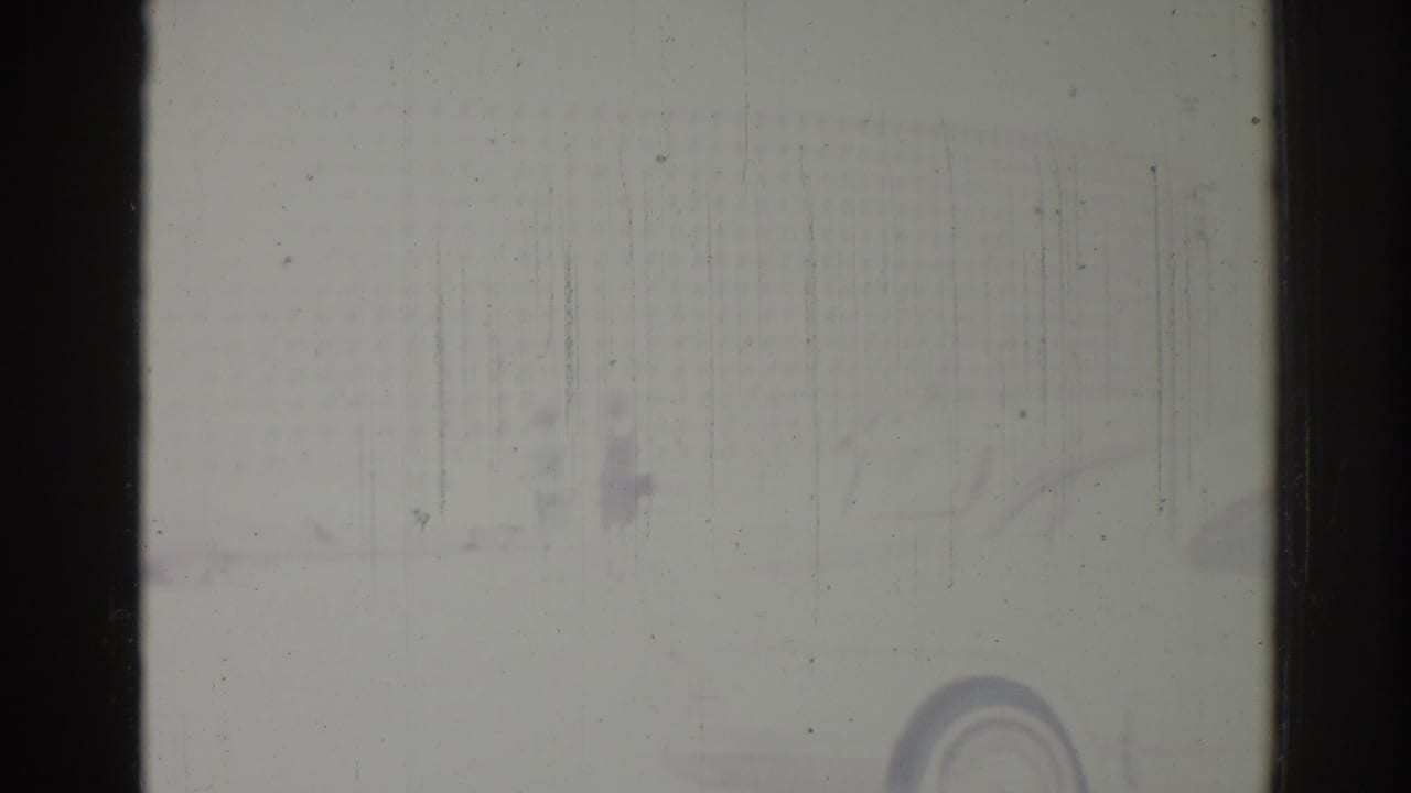 Pale, scratched frame with a dark center divider, faint background marks, and film wear.