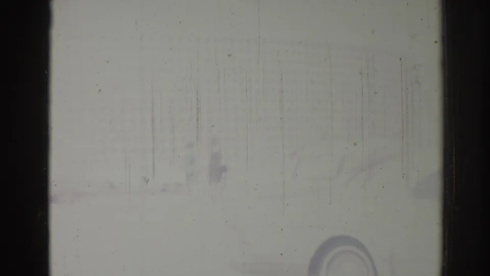 Weathered 1967 Los Angeles 8mm frame showing a dark vertical divider, pale surface, faint marks, dust, and scratches.