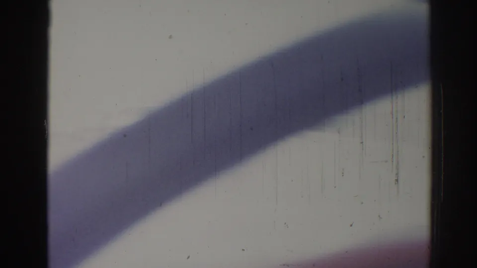 1967 Los Angeles 8mm frame showing a broad diagonal shadow, dark gate edge, pale background, faint circular form, scratches, and dust.
