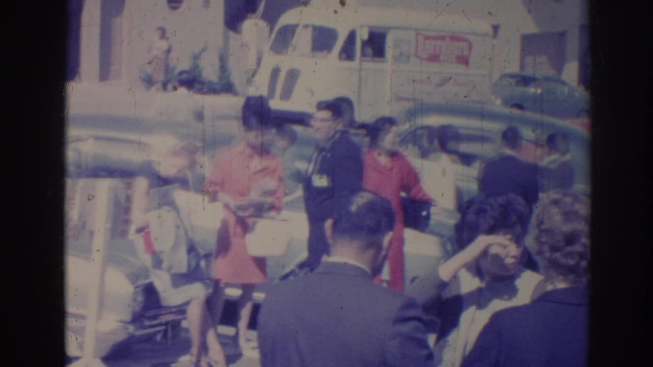 1967 Los Angeles street view with adults in dress clothes near parked cars and a white delivery van.