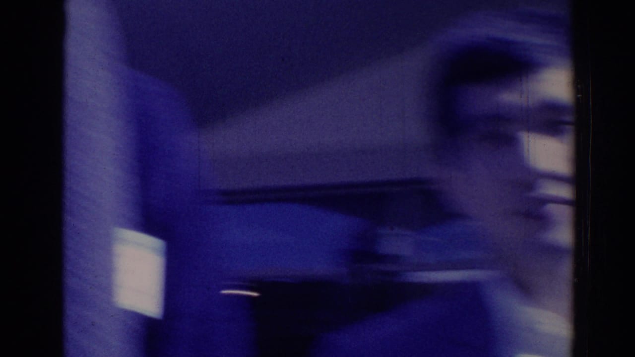 A motion-blurred adult in a dark suit appears close to the camera in this 1967 Los Angeles home-movie frame.