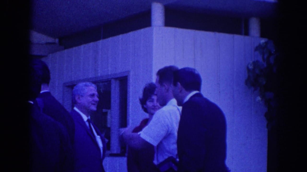 Adults in suits and a woman stand outside a modern building during a conversation.