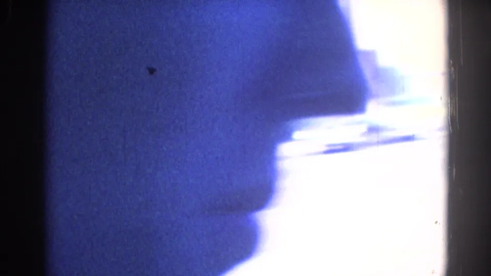 End-frame exposure from the 8mm clip, showing abstract blue shadows, a bright blown-out edge, grain, and a strip of film border.