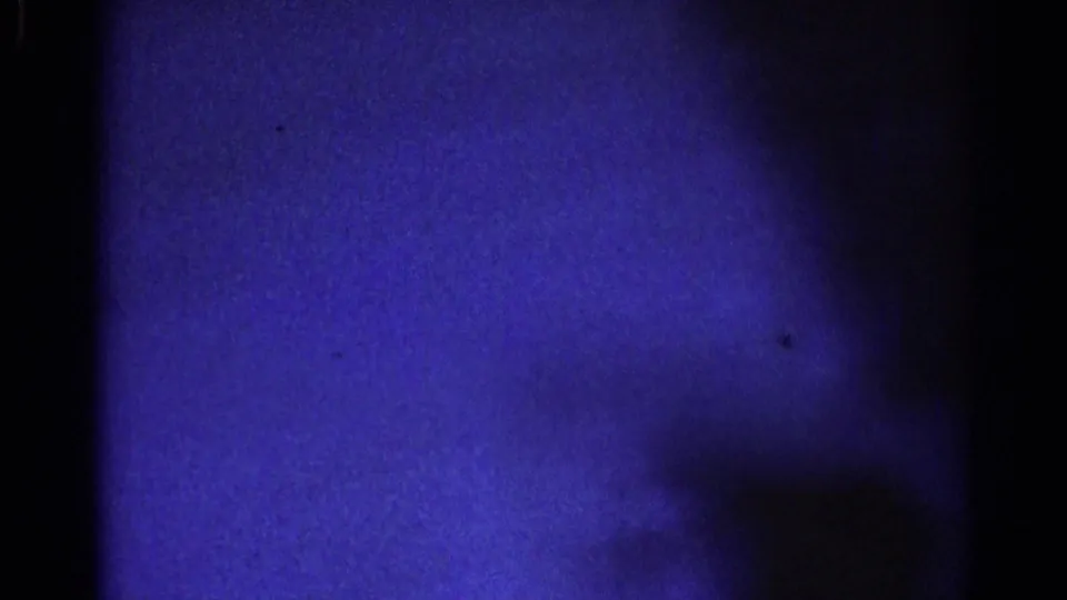 1967 home-movie frame from inside a stationary car, with a blue-shifted partial person or shadowed interior form visible at right.