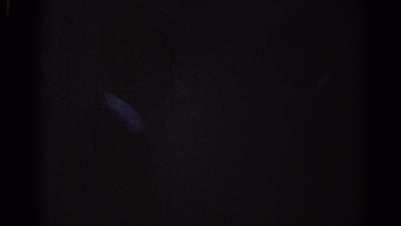Mostly dark frame with a faint diagonal highlight in low-light blue film.