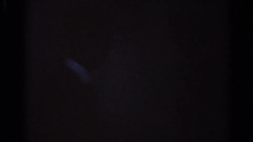 A very dark 8mm frame from the Los Angeles clip shows only a faint highlight and shadowed surroundings.