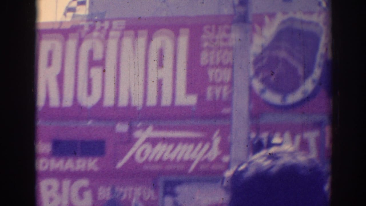 Large red Tommy's sign and adjacent commercial signage on a sunny street.