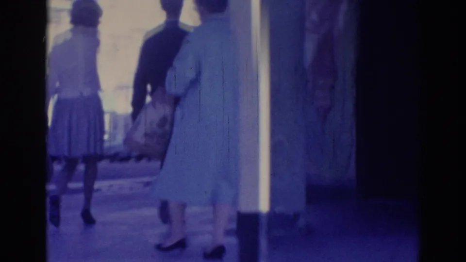 1967 Los Angeles sidewalk view with women in period clothing walking past a storefront or building entrance.