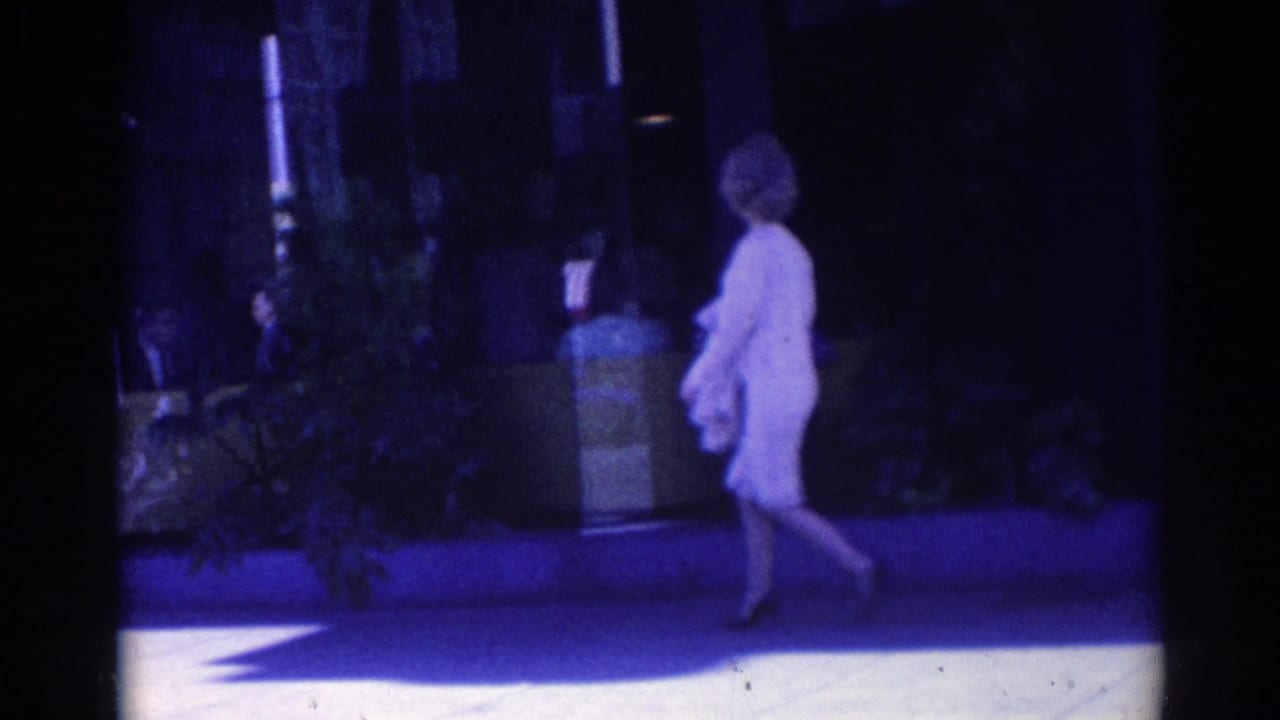 A woman in a light dress and high heels walks along a Los Angeles sidewalk in the 1967 home-movie footage.