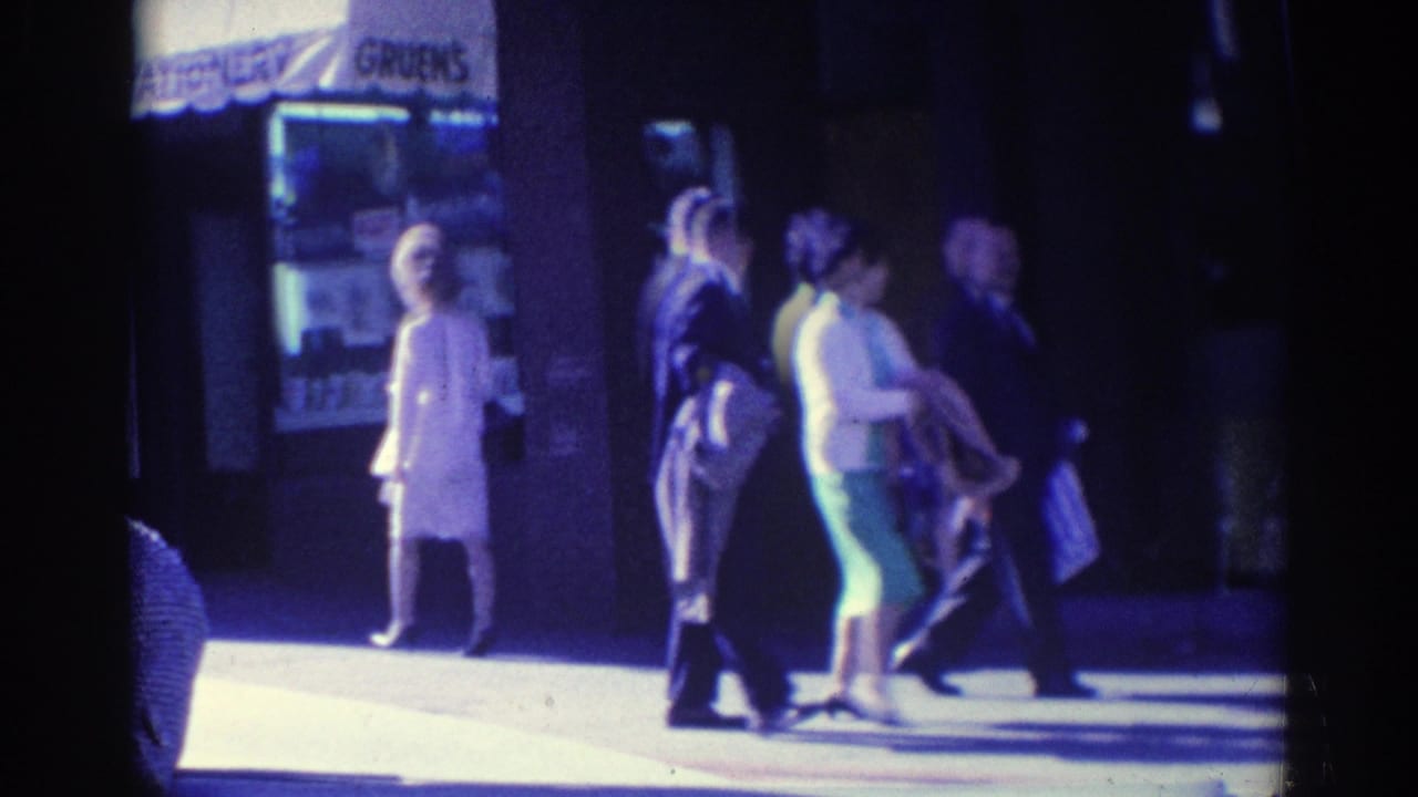 People walk past a storefront with a visible Gruen's sign above the sidewalk.