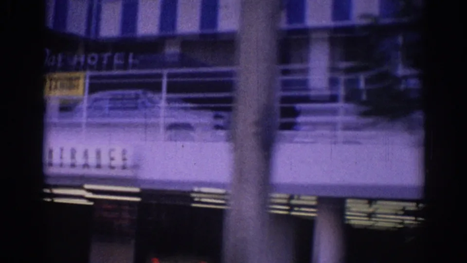 Lower portion of a 1967 Los Angeles hotel exterior, showing partial hotel lettering, a vertical pole, facade stripes, and ground-level windows.