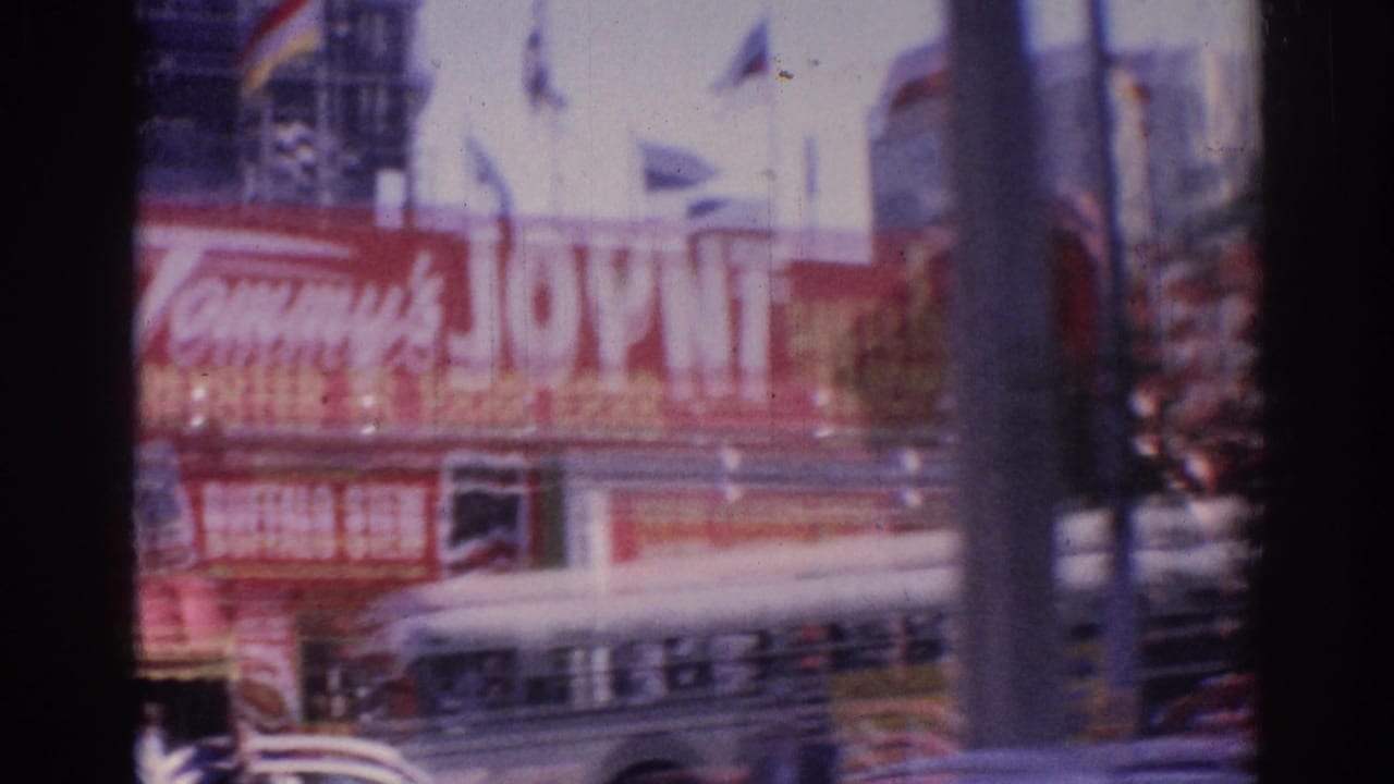 Red Tommy's Joint sign seen from a moving street view with cars and poles in front.