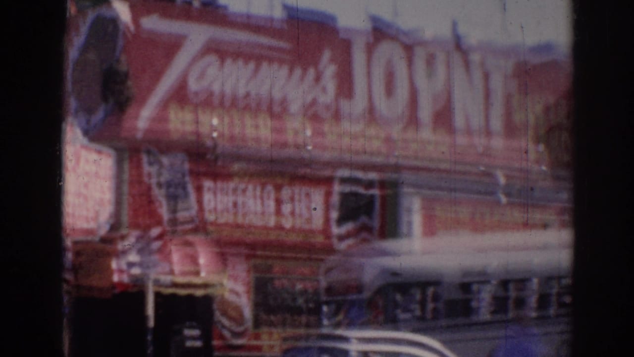 Closer view of the Tommy's Joint sign above a storefront with a car crossing the lower frame.