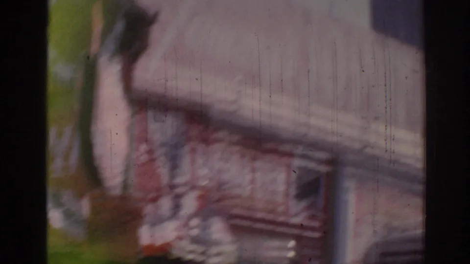 Motion-blurred 8mm frame of the Tommy's Joint exterior, with part of the sign, facade, and street-side objects sliding past.