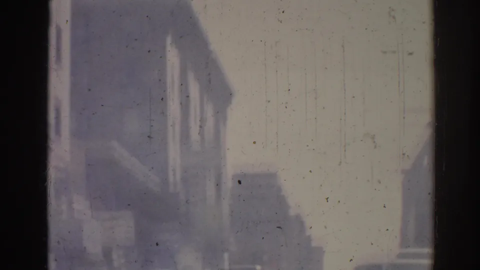 Faded 8mm view of nearby Los Angeles street buildings after the Tommy's Joint sign leaves the frame.