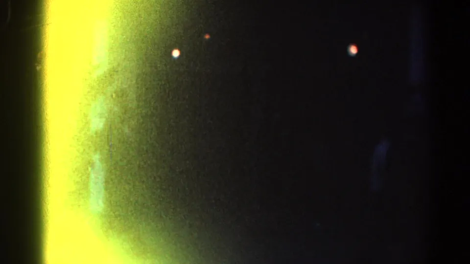 1967 Los Angeles 8mm frame dominated by a yellow light leak or flare, with dark silhouettes and small lights behind it.
