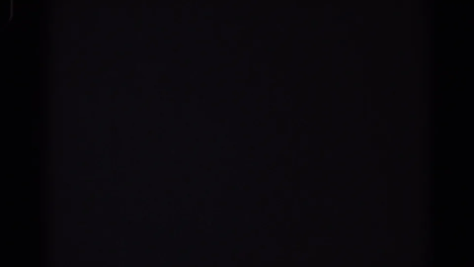 Mostly dark 1967 Los Angeles 8mm frame with faint blue-purple shapes and minimal visible room detail.
