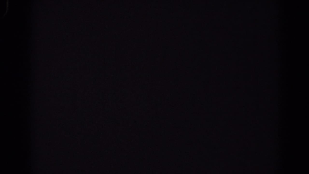 Nearly black film frame with faint texture and no clear subject visible.