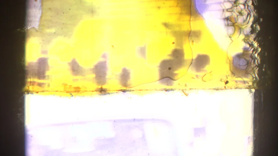 Overexposed 1967 Los Angeles 8mm frame with yellow flare, scratches, and indistinct parade shapes at the edge of visibility.