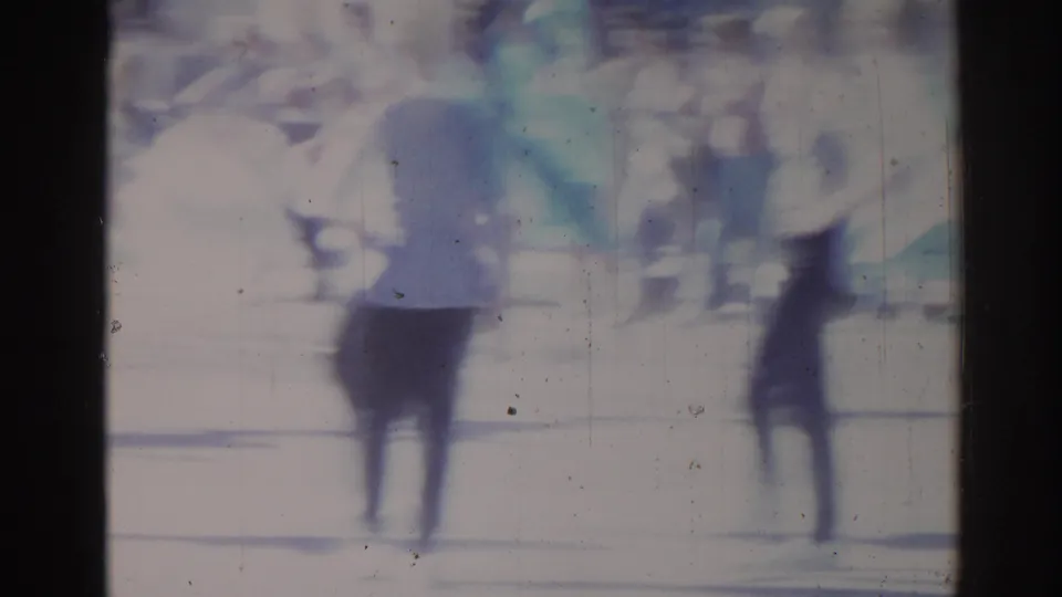 1967 Los Angeles street-parade frame with indistinct pedestrians and spectators softened by motion blur and film grain.