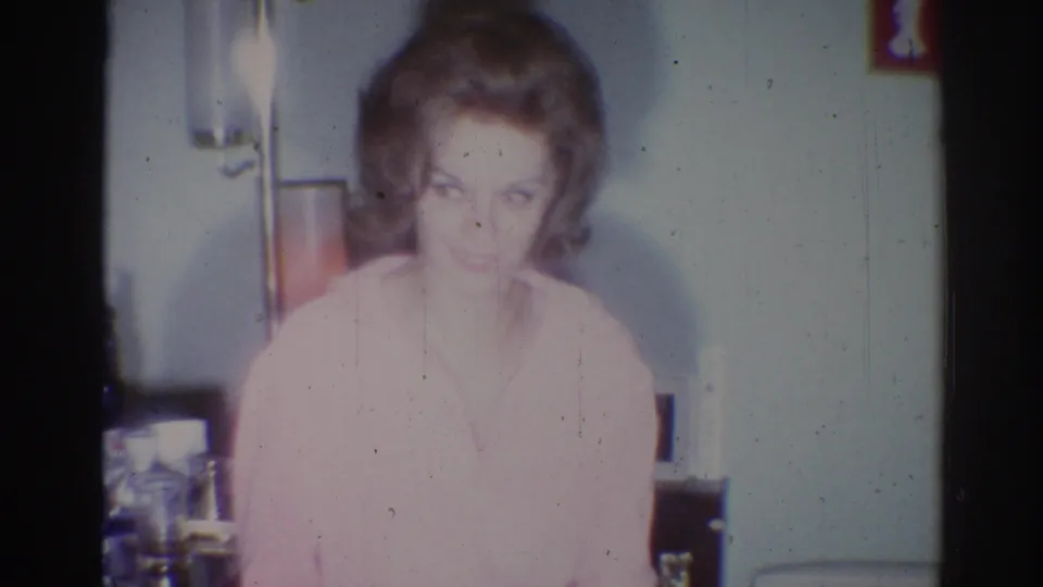In the final frame, the woman in the pink sweater appears to smile toward the camera inside the 1967 Los Angeles private home setting.