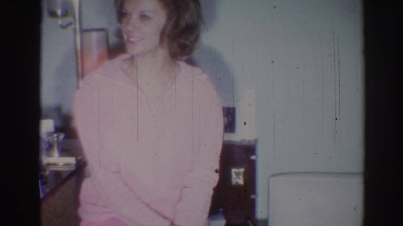 Young woman in a pink sweater turns slightly while smiling in 1967 Los Angeles home-movie footage.