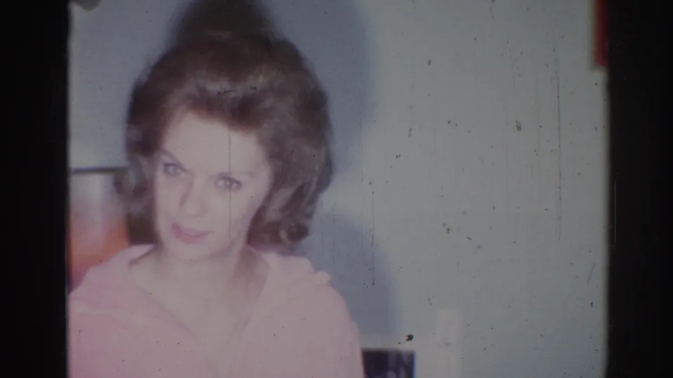 Close view of a young woman in a pink sweater looking toward the camera in 1967 Los Angeles home footage.