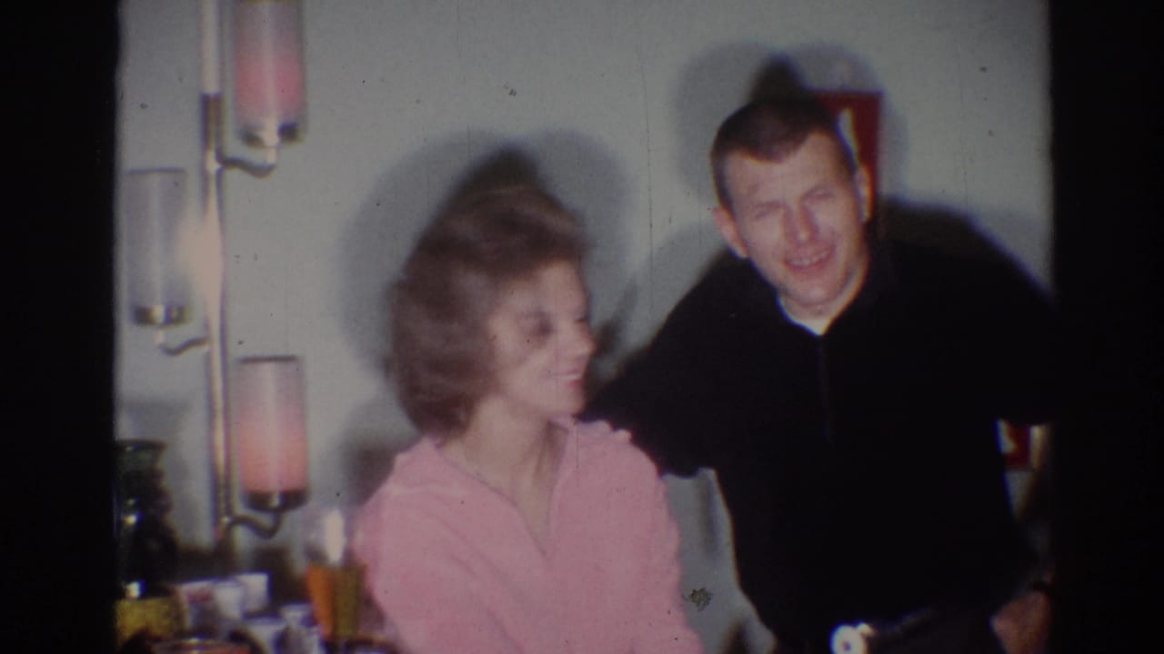 Woman turns toward a man standing close beside her in a home interior.