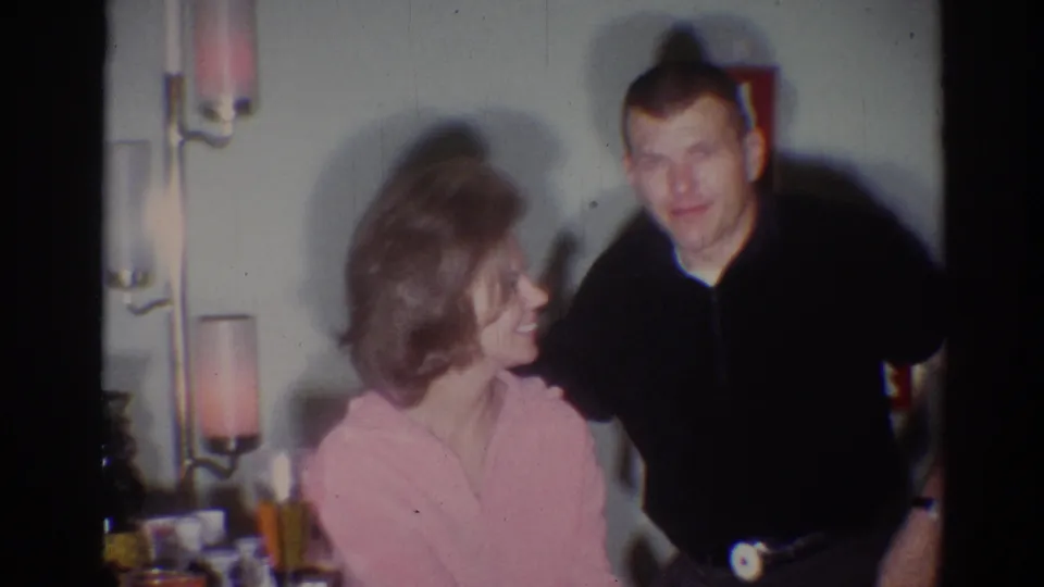 1967 Los Angeles home-movie frame showing the couple exchanging a warm glance inside a softly lit room.