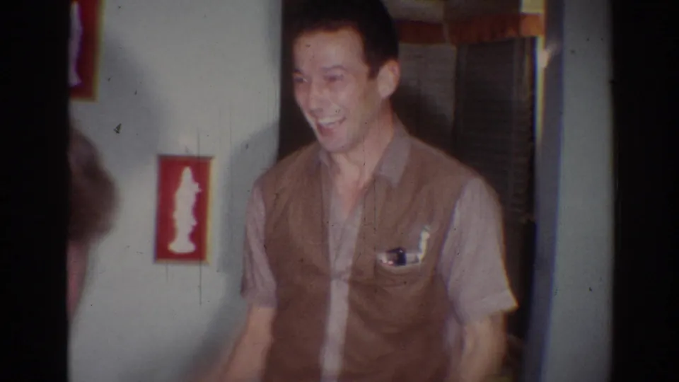A man in a brown vest laughs and gestures in a private Los Angeles home interior, consistent with the 1967 home-movie metadata.