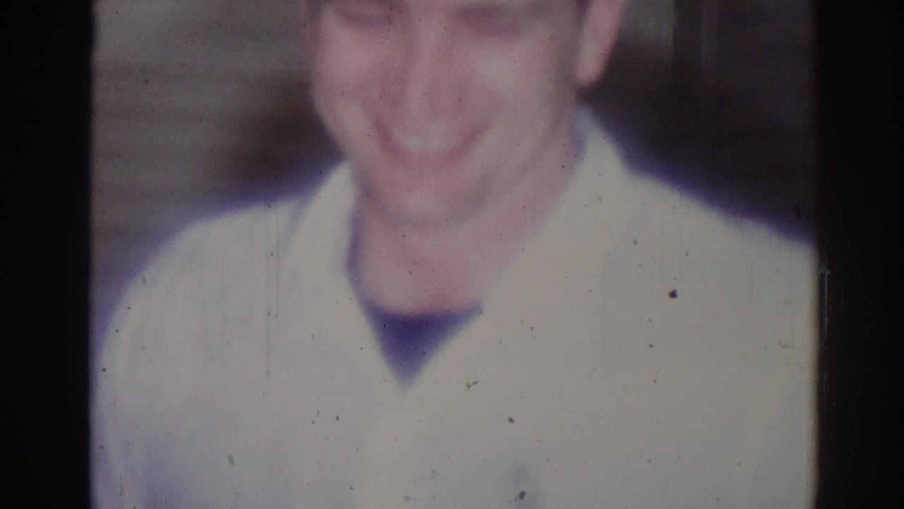 Soft close-up of a smiling young man wearing a white martial arts gi.