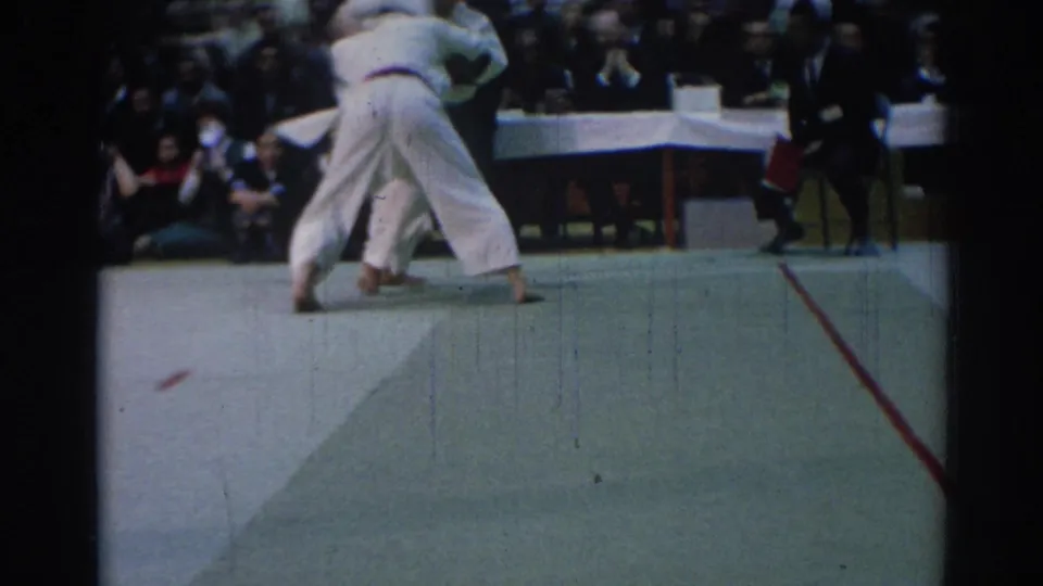 1967 Los Angeles judo championship frame with athletes in white gi locked together near the edge of the competition mat.