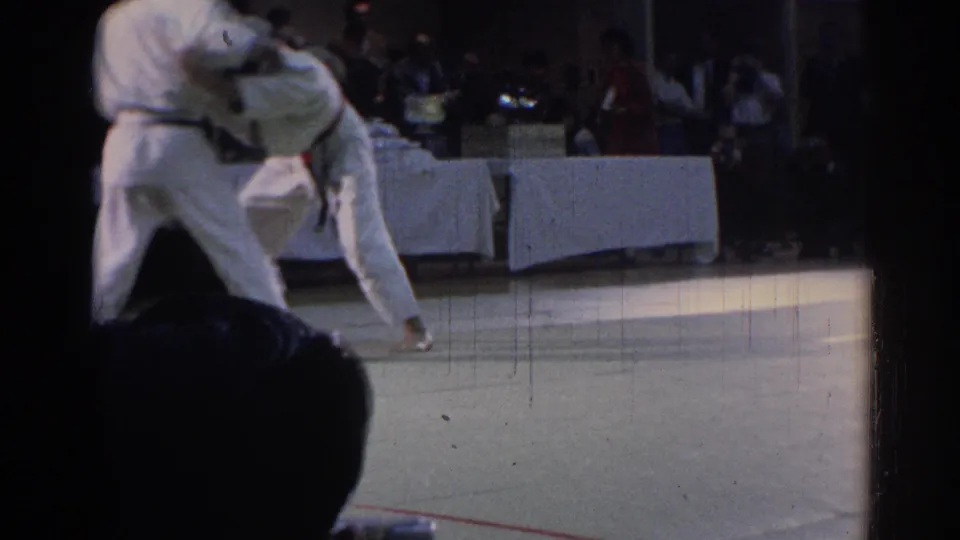 The 1967 Los Angeles footage shows a dynamic grappling moment as one gi-clad competitor lifts or turns the other on the mat.