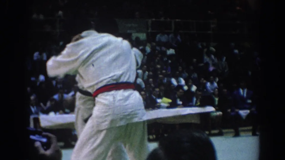 Two white-gi judo athletes grapple during the Los Angeles match, with spectators visible behind the mat.